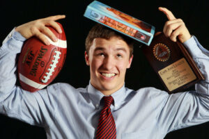 student with books and a football ball